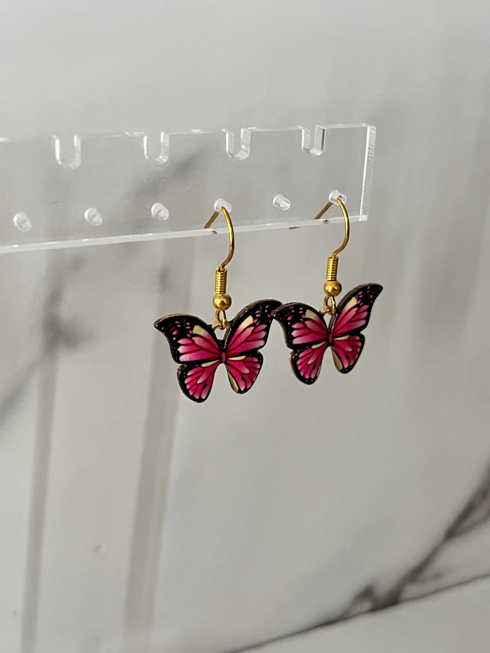 Gold earrings with pink or purple butterfly design

