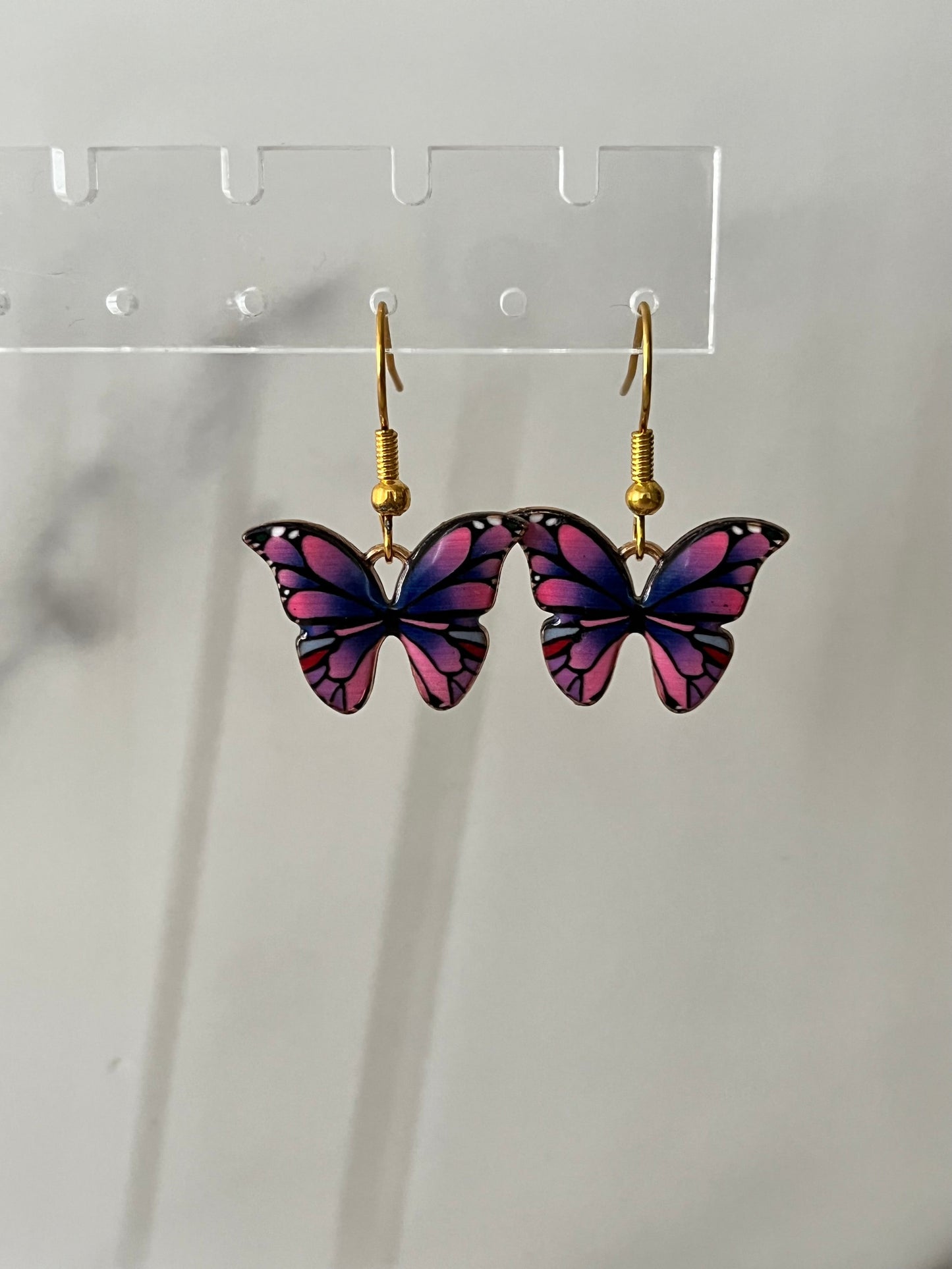 Gold earrings with pink or purple butterfly design

